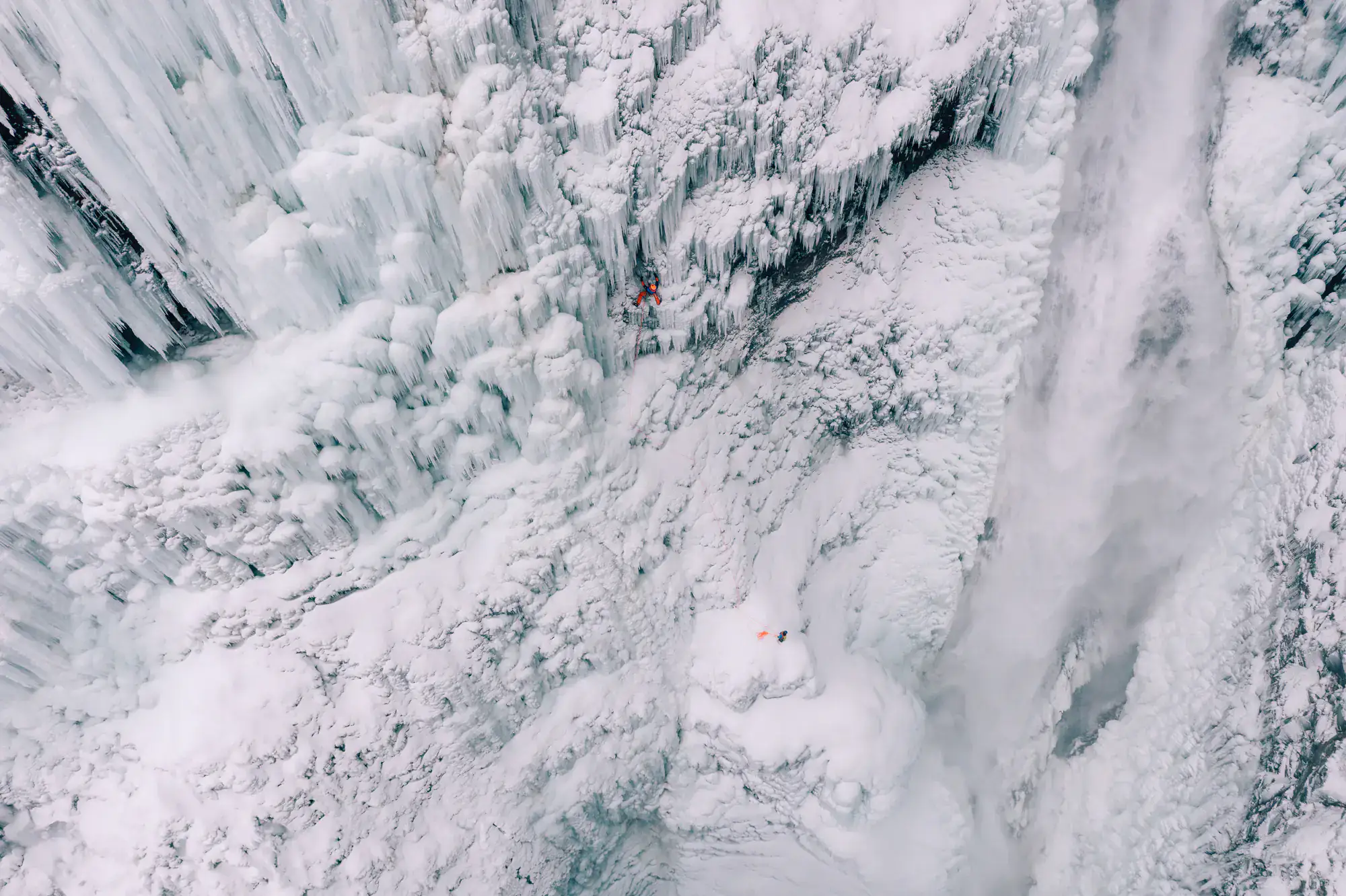 Eiskletterer an einer breiten, vereisten Wasserfallwand in Island