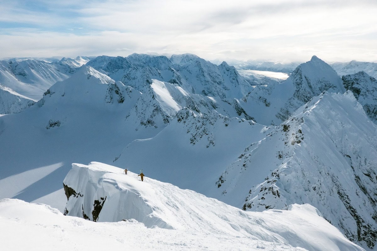 Zwei Skitourengeher auf einem verschneiten Grat über den Gipfeln der Lyngenalpen