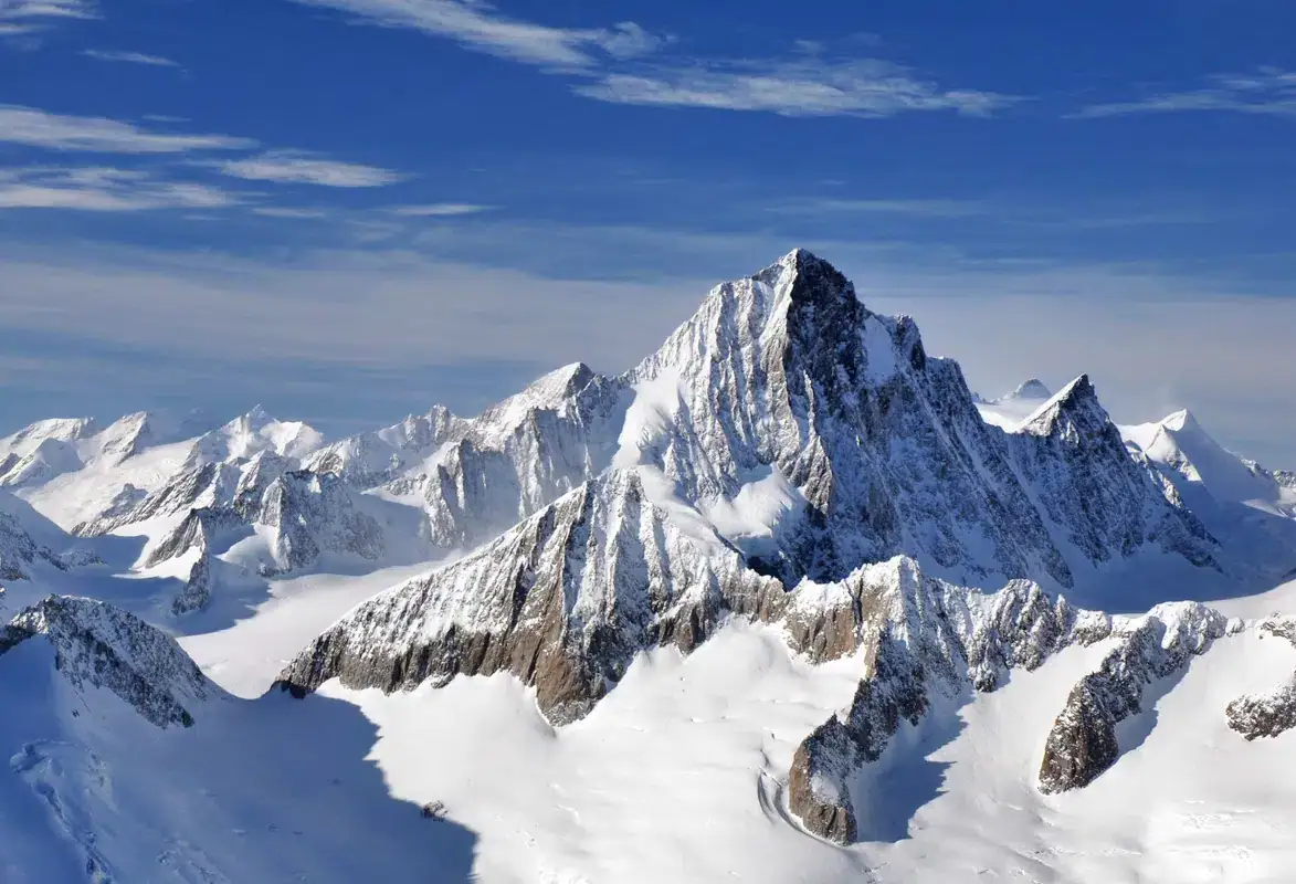 Steile Felspyramide des Finsteraarhorns über weiten Gletscherbecken unter blauem Himmel
