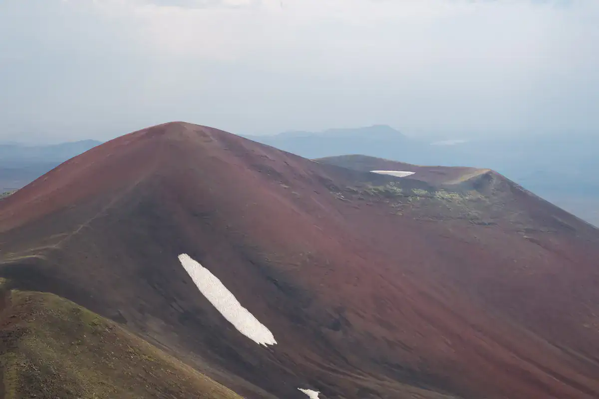 Rotbrauner Vulkankamm mit Schneefeldern im Ghegama Gebirge in Armenien