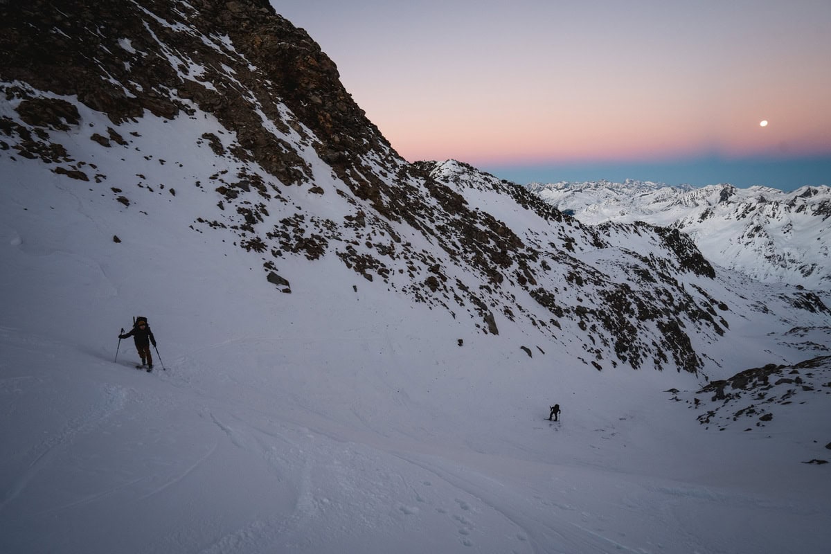 Zwei Skitourengeher im Aufstieg in einer Flanke im Abendrot