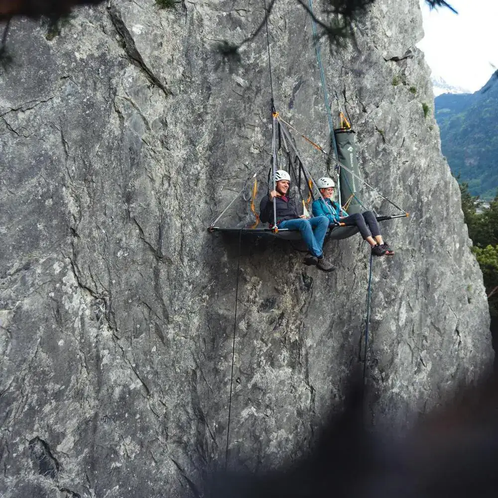 Zwei Personen sitzen auf einem Portaledge in einer Felswand