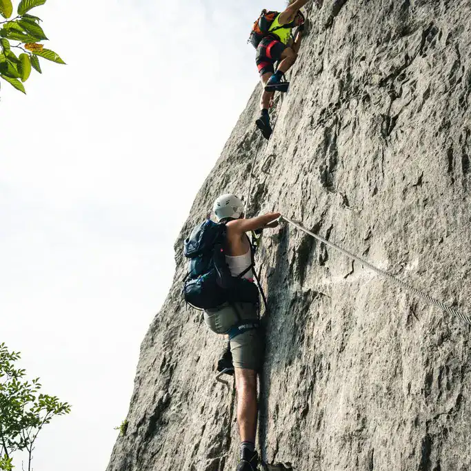 Zwei Personen am Drahtseil einer steilen Klettersteigwand