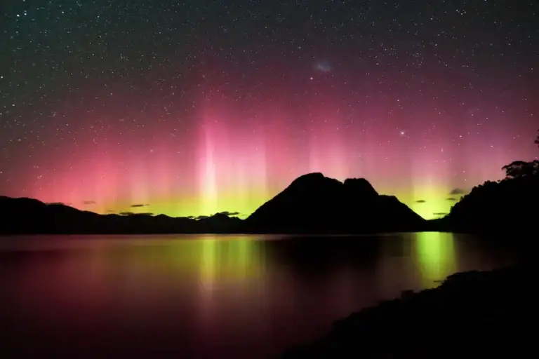 Rot-grünes Polarlicht mit Sternenhimmel über einem stillen See