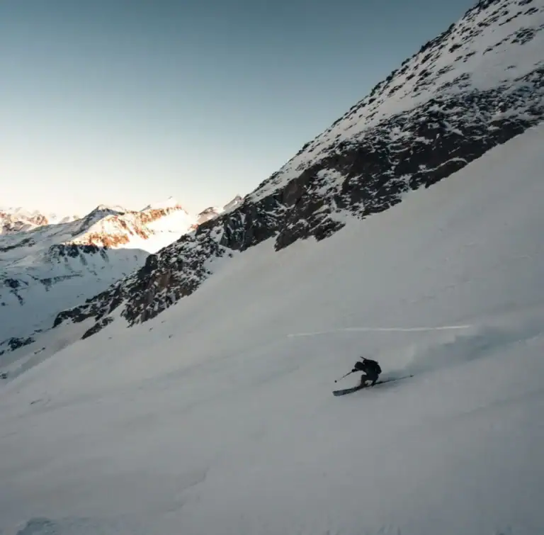 Skifahrer in einer weiten Pulverschneeflanke im Morgenlicht