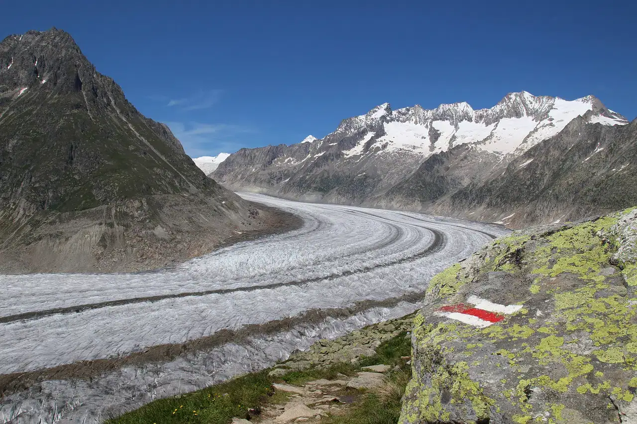 Aletschgletscher mit Wanderwegmarkierung auf einem Felsblock im Vordergrund
