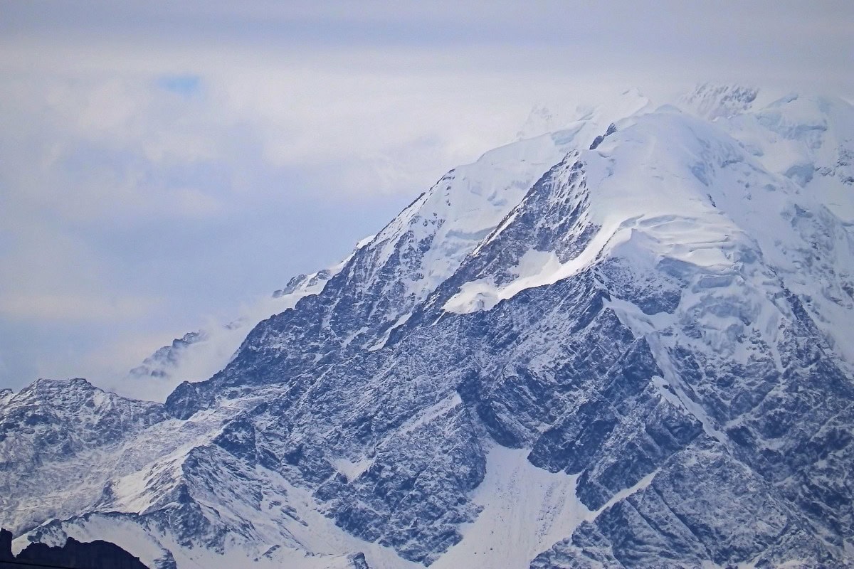 Vergletscherte Gipfelflanken des Illimani über einem Wolkenband