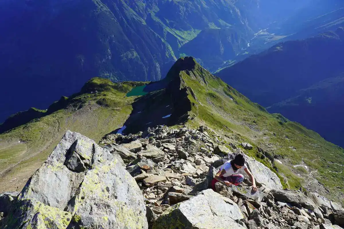 Wanderin rastet auf einem felsigen Gipfelgrat über dem Tal