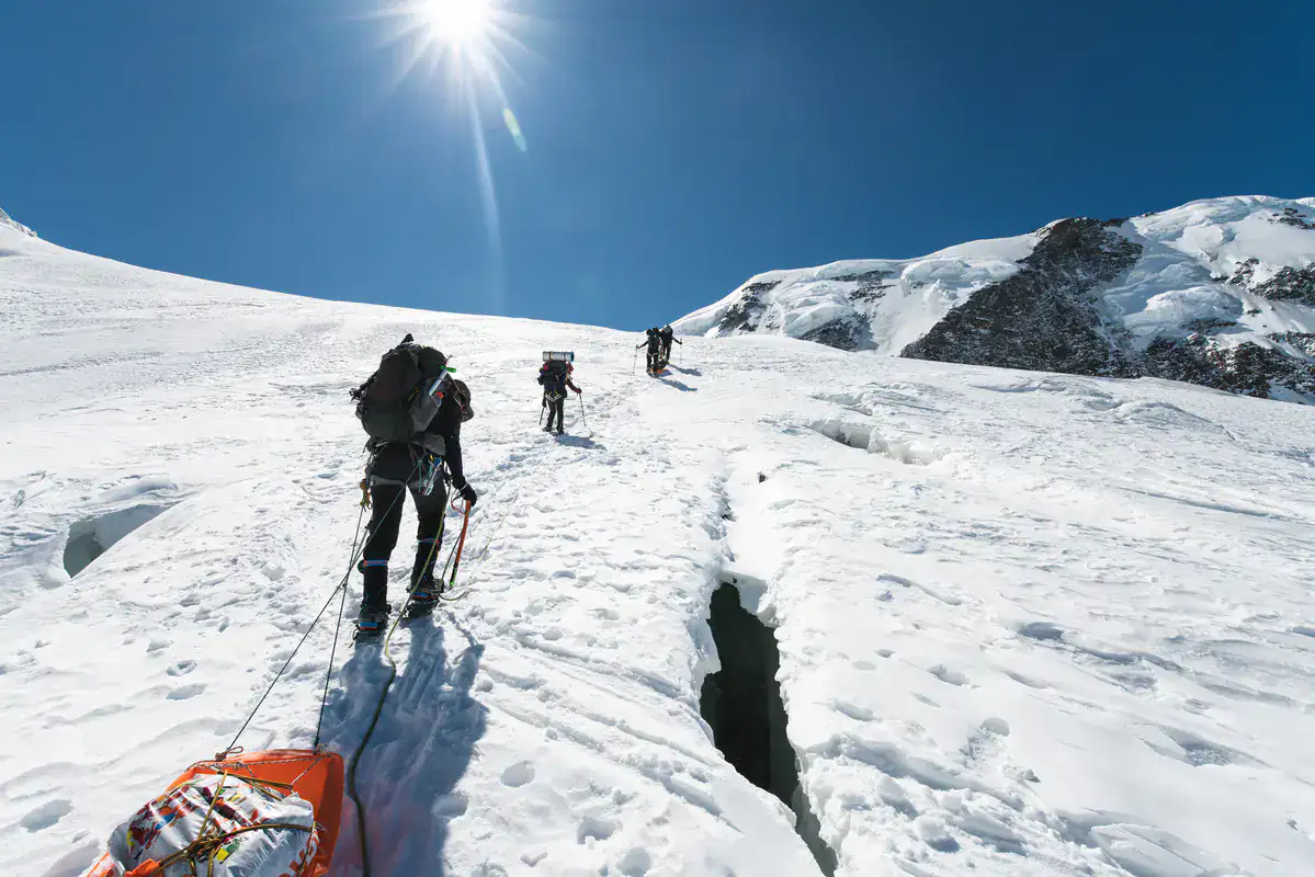 Seilschaft überquert bei Sonnenschein einen spaltenreichen Gletscher