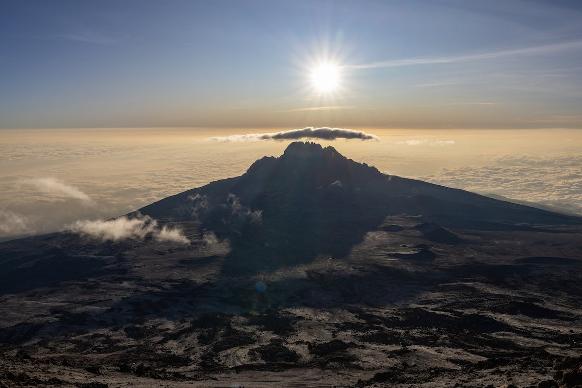 Zackiger Gipfel des Kilimandscharo im Gegenlicht über einem Wolkenmeer