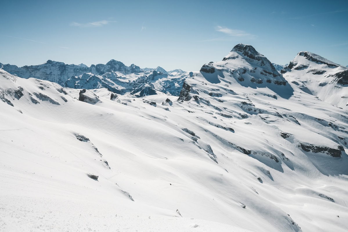 Verschneite Berggipfel über einem weiten Schneehang