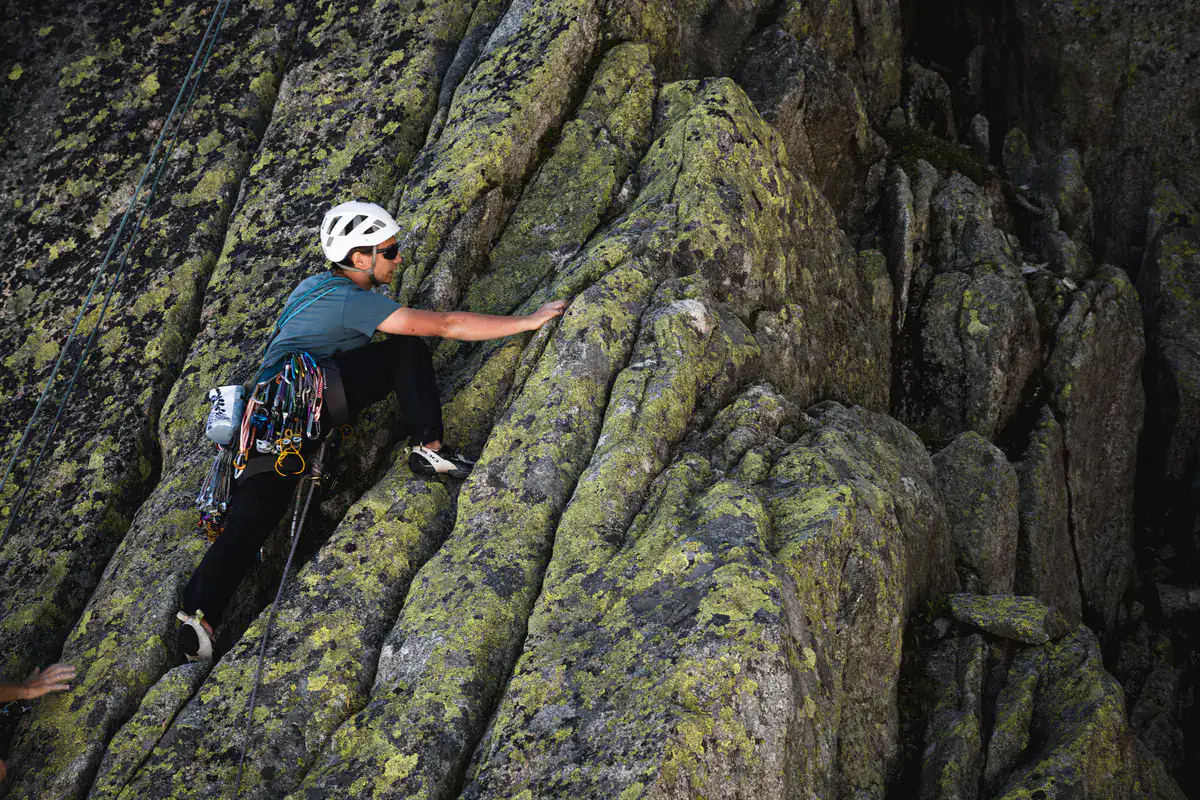 Kletterin mit Klemmgeräten am Gurt an einer Granitplatte