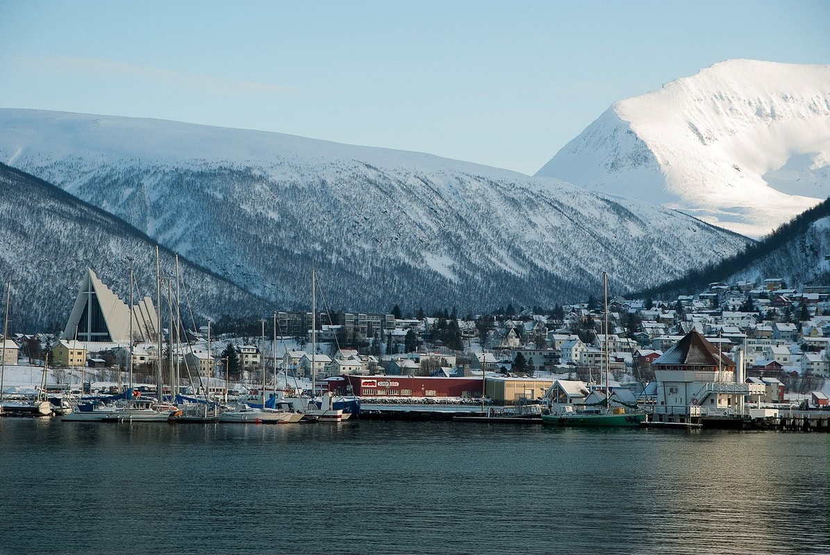 Hafen von Tromsø mit Segelbooten und Eismeerkathedrale vor verschneiten Bergen