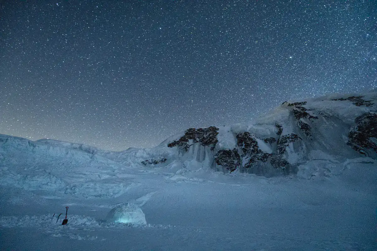 Verschneite Berglandschaft bei Nacht unter dem Sternenhimmel