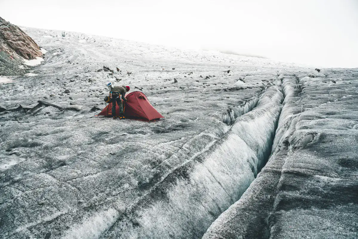 Rotes Zelt auf einem Gletscher neben einer Gletscherspalte
